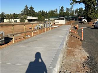 the front sidewalk that goes along the parking area, currently dirt, and in front of the admin building