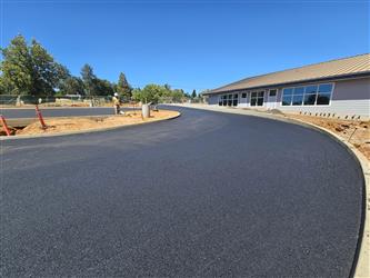 a large curve of freshly installed asphalt turning in front of the kindergarten wing