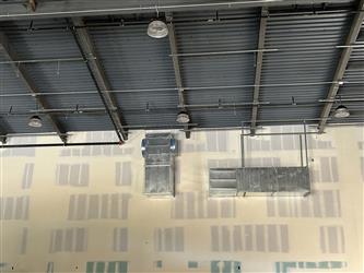 A wall of the multipurpose room interior with taped drywall and exposed silver HVAC ducting