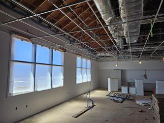 the inside of a classroom with windows and drywall installed and exposed wood framing roofing and ventilation ducts