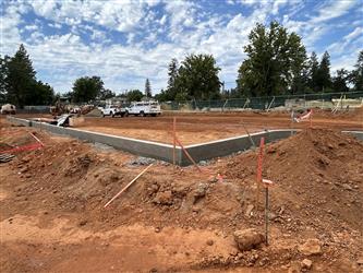 a small retaining wall around a very large dirt area being graded for the parking lot
