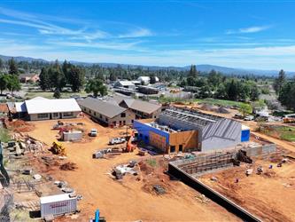 a drone shot facing South East showing Buildings A, B, C, and D along with a large retaining wall to the West of Building A