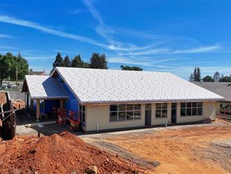 Building B shown without roofing installed and partial siding completed surrounded by dirt and heavy equipment