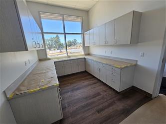 an office interior with large windows, upper and lower cabintry and wood panel flooring