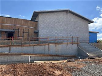 the exterior of the multipurpose room made of CMU block and exposed wood framing.  There is a large concrete ramp under construction