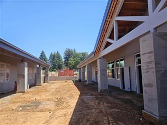 two classroom buildings with blue horizontal siding and large square concrete pillars with dirt between the buildings