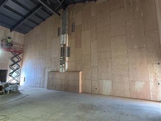 a large wall in the multipurpose room covered in plywood