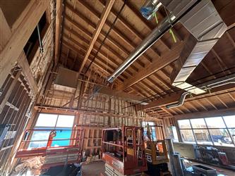 the high roof of the inside of the new kindergarten wing with exposed hvac duct work and man lifts on the ground