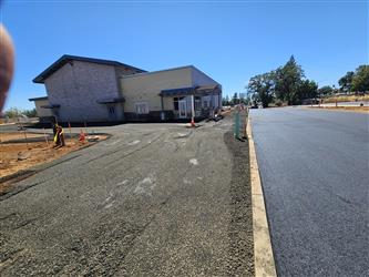 the curb separating the new asphalt dropoff area in front of the multipurpose room and gravel prepped for a concrete pour for sidewalks