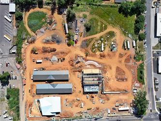 A drone shot pointing straight down over the entire property showing many dirt paths and heavy equipment along with the 4 buildings under construction
