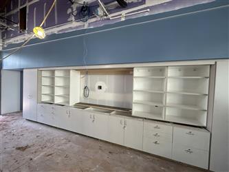 a teaching wall in a typical classroom with shelving and storage cabinets and a blue accent soffit above