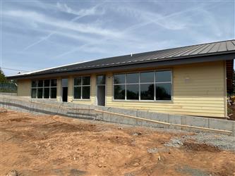 The side of a building with metal roofing and unpainted siding and windows