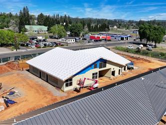 a high drone shot pointing North East showing dirt paths and building B with siding being installed and ready for roofing