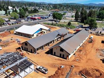 a drone shot of buildings B, C, and D point to the East showing nearly completed metal roofing and wood siding surrounded by dirt
