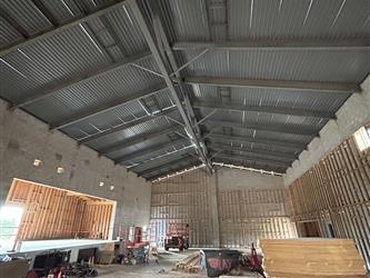 A large CMU block building with concrete floor and large steel trusses with an exposed metal roof