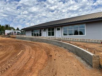 A large graded dirt area for the parking lot adjacent to a planter wall near the TK-K classroom wing
