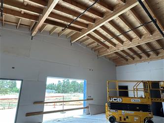The interior of the stage in the multipurpose room with exposed wood rafters and drywall on the walls