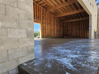 a large concrete stage with color dye splashed on the stage alongside a CMU block wall and a wood framed ceiling over the back of the stage