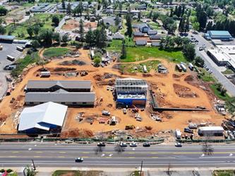 a high drone shot pointing South showing many dirt paths across the property and the 4 buildings under construction