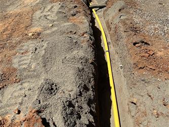 a large orange conduit sitting in a dirt trough