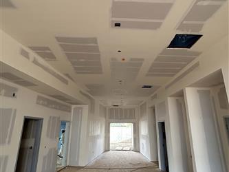 a long interior hallway with an unfinished concrete floor and taped drywall