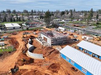 A large concrete block building and 2 long classroom buildings under construction.