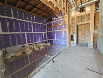 a building interior with installed drywall with taping and striping and corrugated steel panels installed on the floor surrounded by wood framing