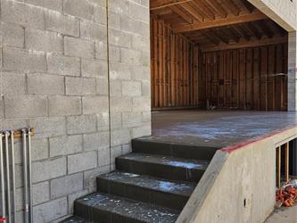 A set of concrete stairs leading up to a stage next to a CMU block wall