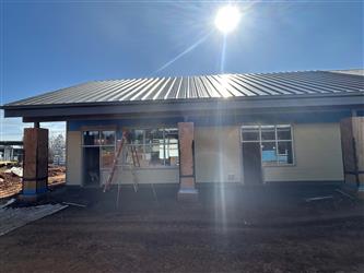 a classroom building with large columns supporting the metal roof and horizontal siding being installed