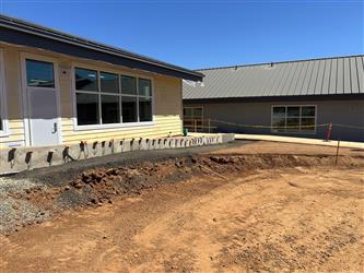 A small retaining wall between the landscaping and the front parking lot near the TK-K classroom wing