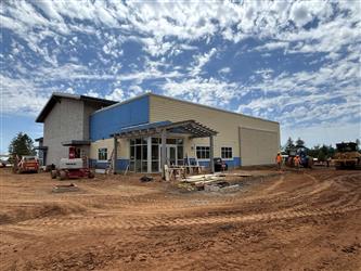 The large multipurpose room with office in the front. Siding is installed and the ground is dirt
