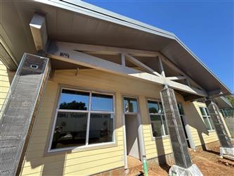 an external view of the classroom building with unpainted siding, windows, exposed pilars and steal framing