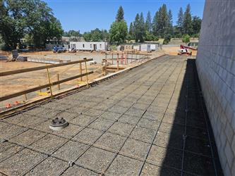 gravel pathways with rebar laid out alongside the CMU block wall of the cafeteria.