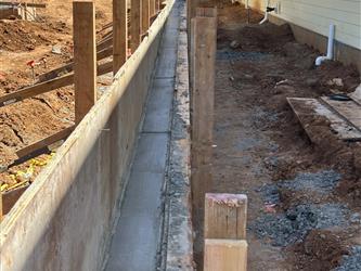 wood frames and concrete poured for a retaining wall next to a classroom building