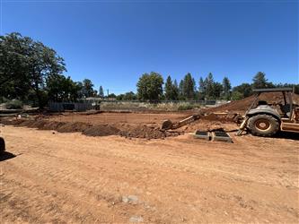 a small tractor begins the grading on the dirt for the front parking lot