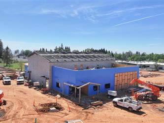 a high drone shot pointing South showing many dirt paths and building A with most wood framing completed and ready for roofing