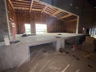 a large concrete stage in Building A with wood framed ceiling above the stage.